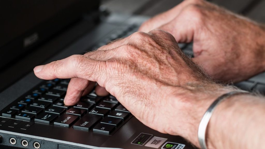 man's hands typing on laptop