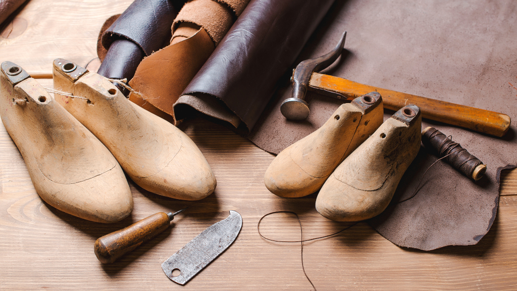 Photo to announce website redesign: Leather in rolls, cobbler tools and shoe lasts in workshop